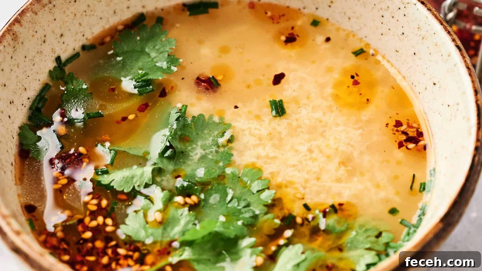 31 Asian Weeknight Dinners to Make Mealtime Exciting 22 A comforting bowl of egg drop soup elegantly garnished with fresh cilantro, vibrant chives, and a sprinkle of chili flakes.