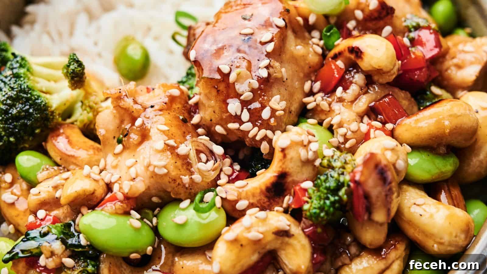 31 Asian Weeknight Dinners to Make Mealtime Exciting 27 Close-up of Cashew Chicken featuring tender chicken, broccoli, edamame, cashews, and red bell peppers. This delightful dish is topped with sesame seeds and served over a bed of rice.