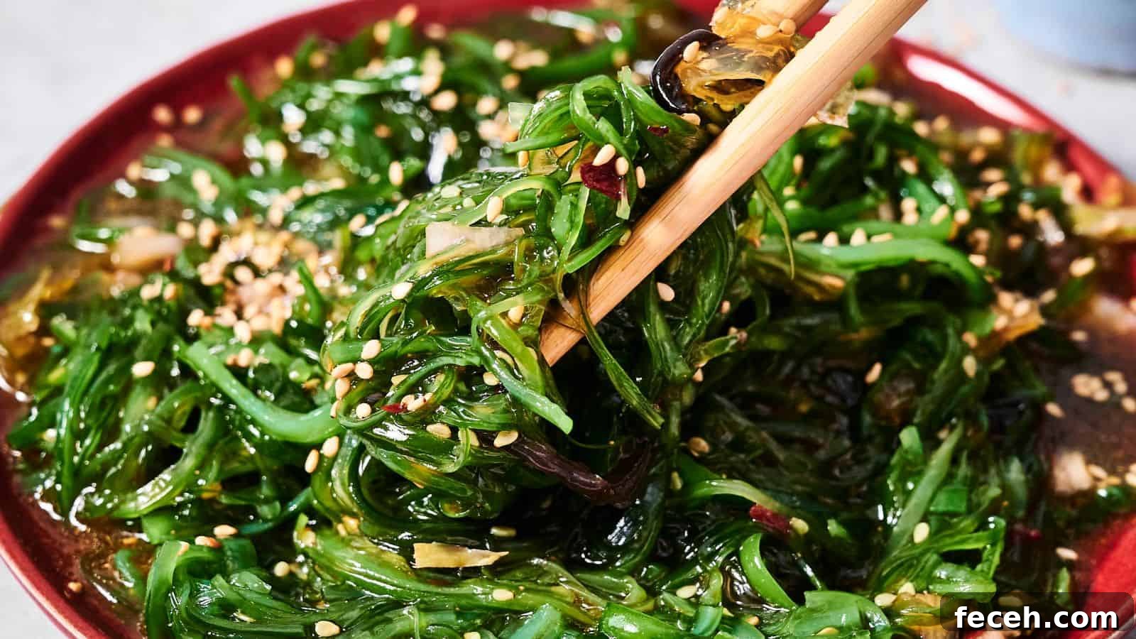 31 Asian Weeknight Dinners to Make Mealtime Exciting 7 A close-up of seaweed salad with sesame seeds on a red plate, with chopsticks picking up a portion.