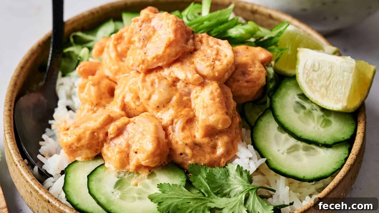 31 Asian Weeknight Dinners to Make Mealtime Exciting 10 A bowl of rice topped with shrimp in a creamy sauce, garnished with cucumber slices, lime wedge, cilantro, and sliced green onions.
