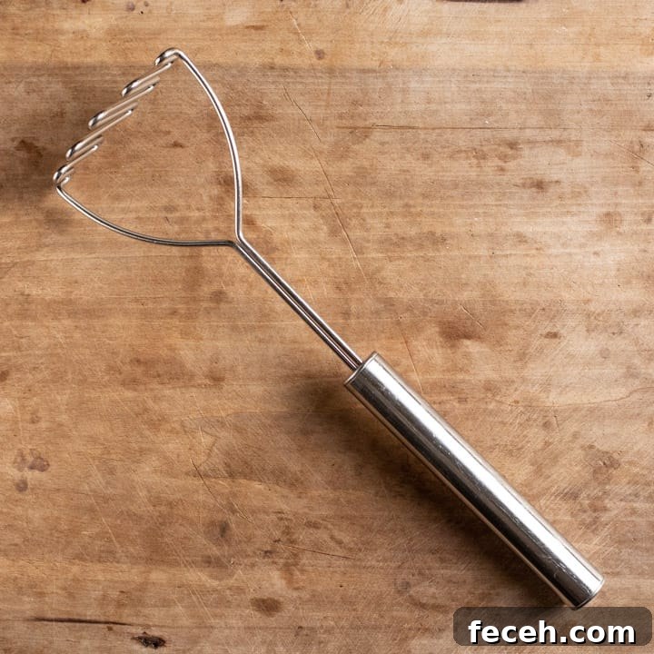 wooden background with silver potato masher on