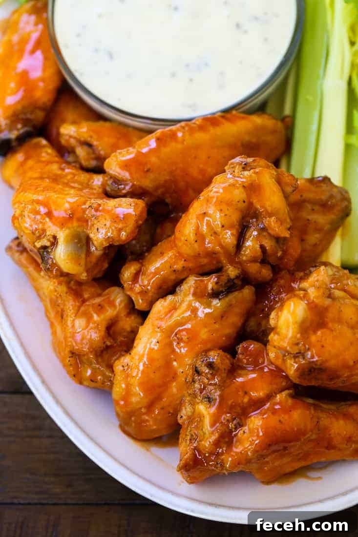 These Crispy Buffalo Chicken Wings are SO addicting and fall off the bone tender! A few tips make them as crispy as if you fried them! buffalo chicken wings stacked on a platter
