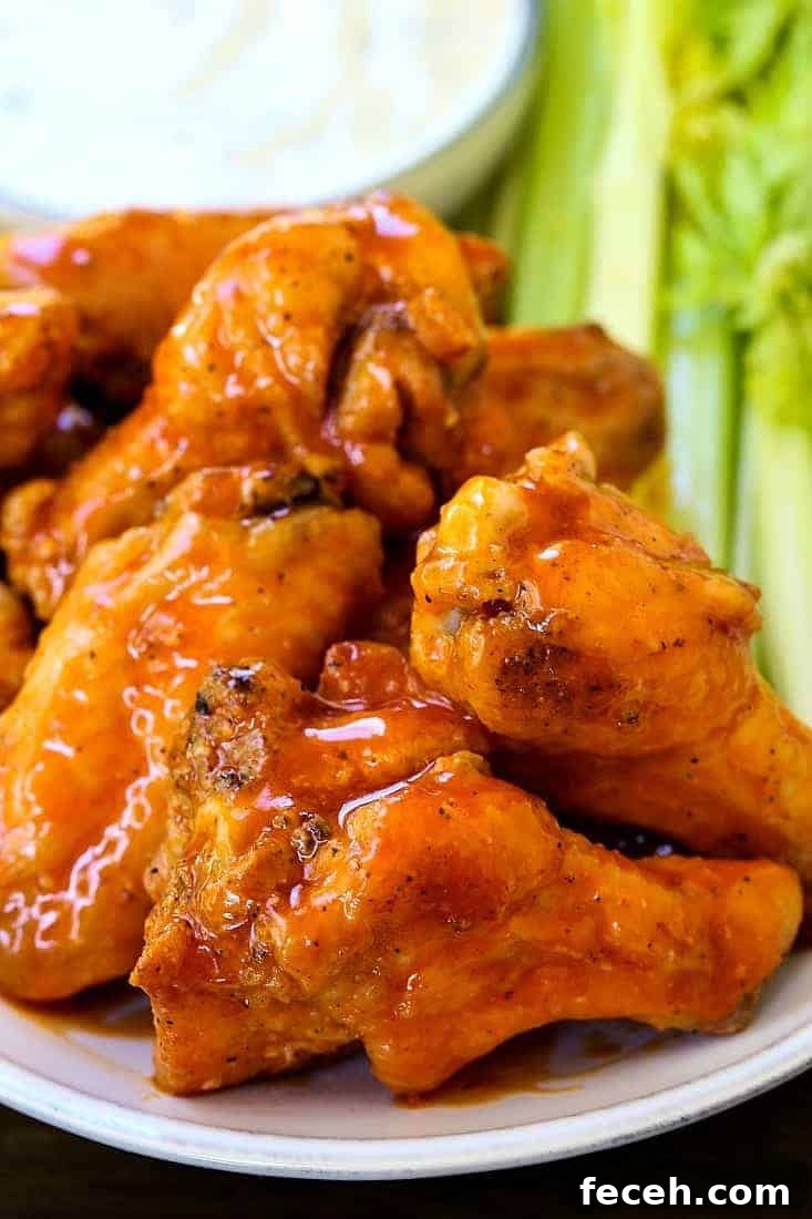 These Crispy Buffalo Chicken Wings are SO addicting and fall off the bone tender! A few tips make them as crispy as if you fried them! baked buffalo chicken wings stacked on a platter
