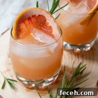 two glasses of grapefruit vodka cocktails with fresh rosemary laying next to it
