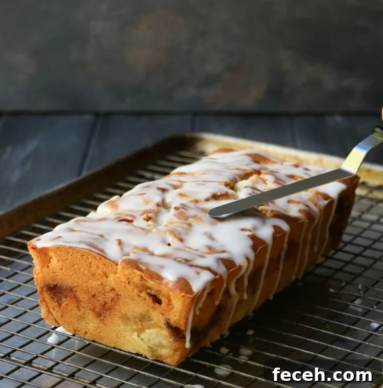 A spatula spreads glaze over the top of Apple Fritter Bread