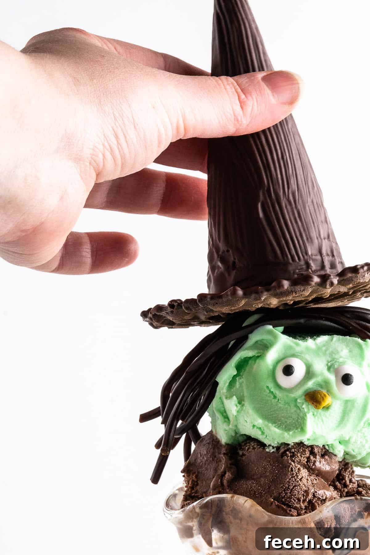 hand placing chocolate witch hat on sundae