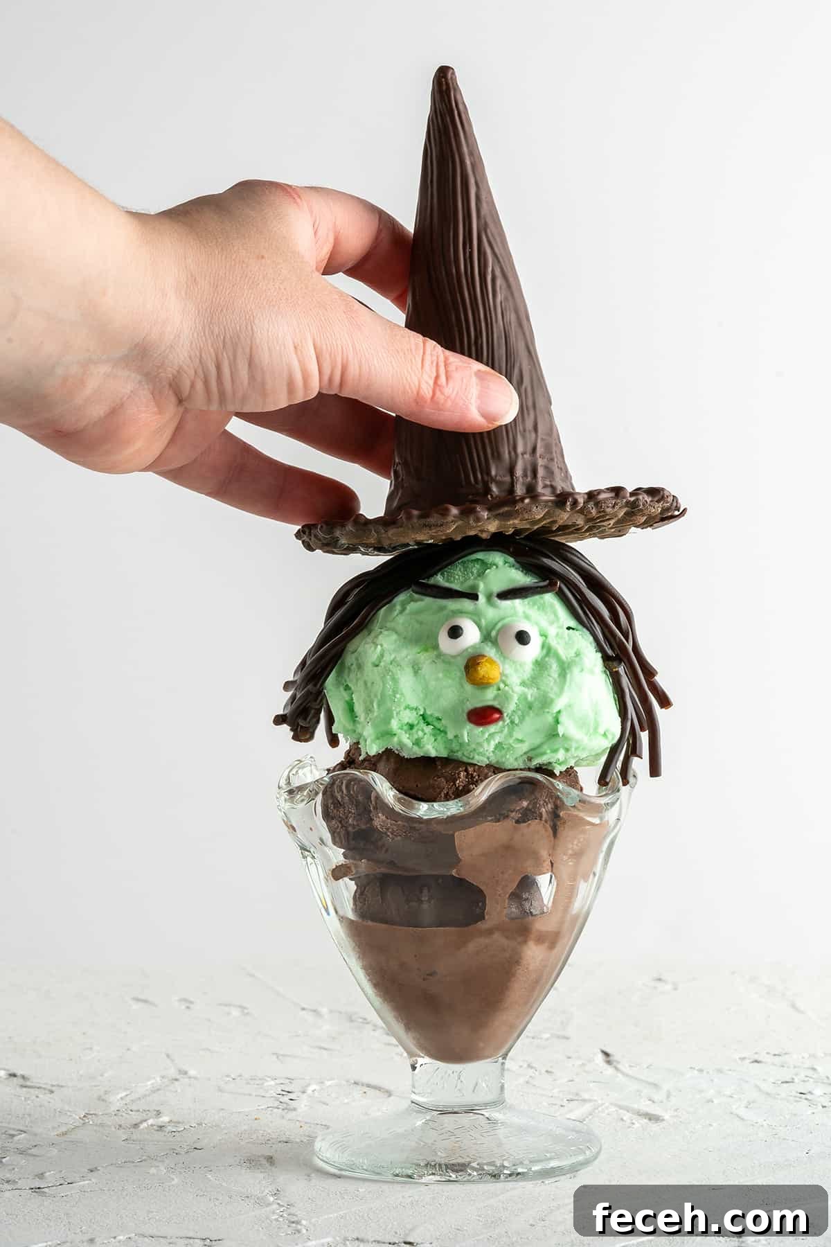 Hand placing witch hat on Halloween sundae