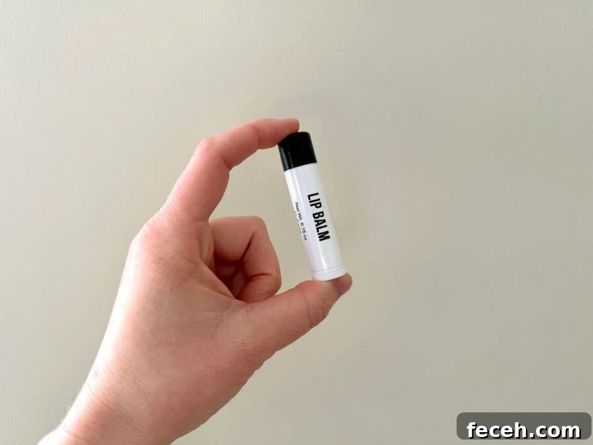 Are Public Goods Products Worth It? A Deep Dive Into Their Ingredients 9 Hand holding Public Goods lip balm tube with black cap against beige wall