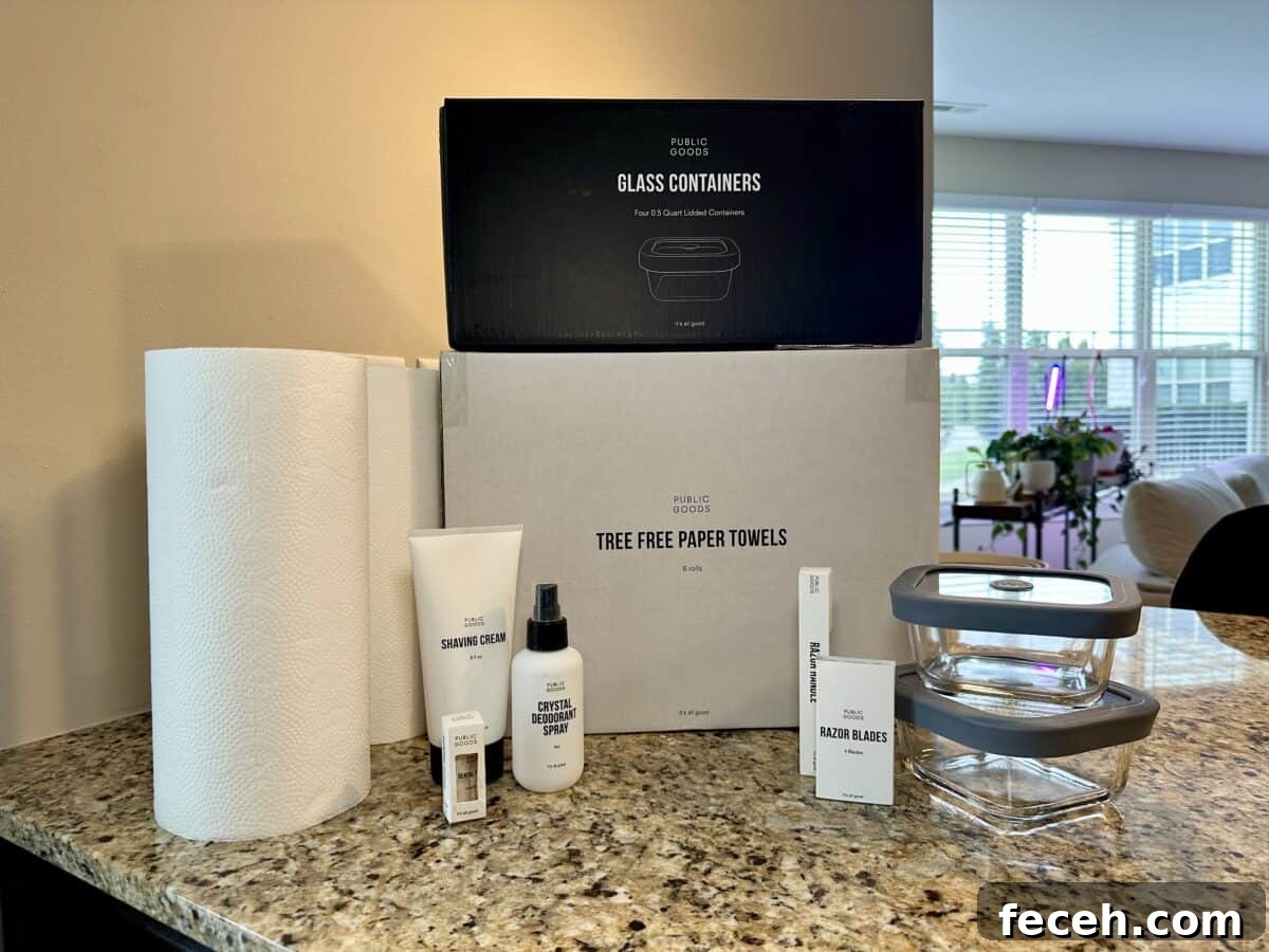Are Public Goods Products Worth It? A Deep Dive Into Their Ingredients 10 A collection of Public Goods products displayed on a granite kitchen counter, including tree-free paper towels, glass food containers with gray lids, shaving cream, crystal deodorant spray, razor blades, and a razor handle.