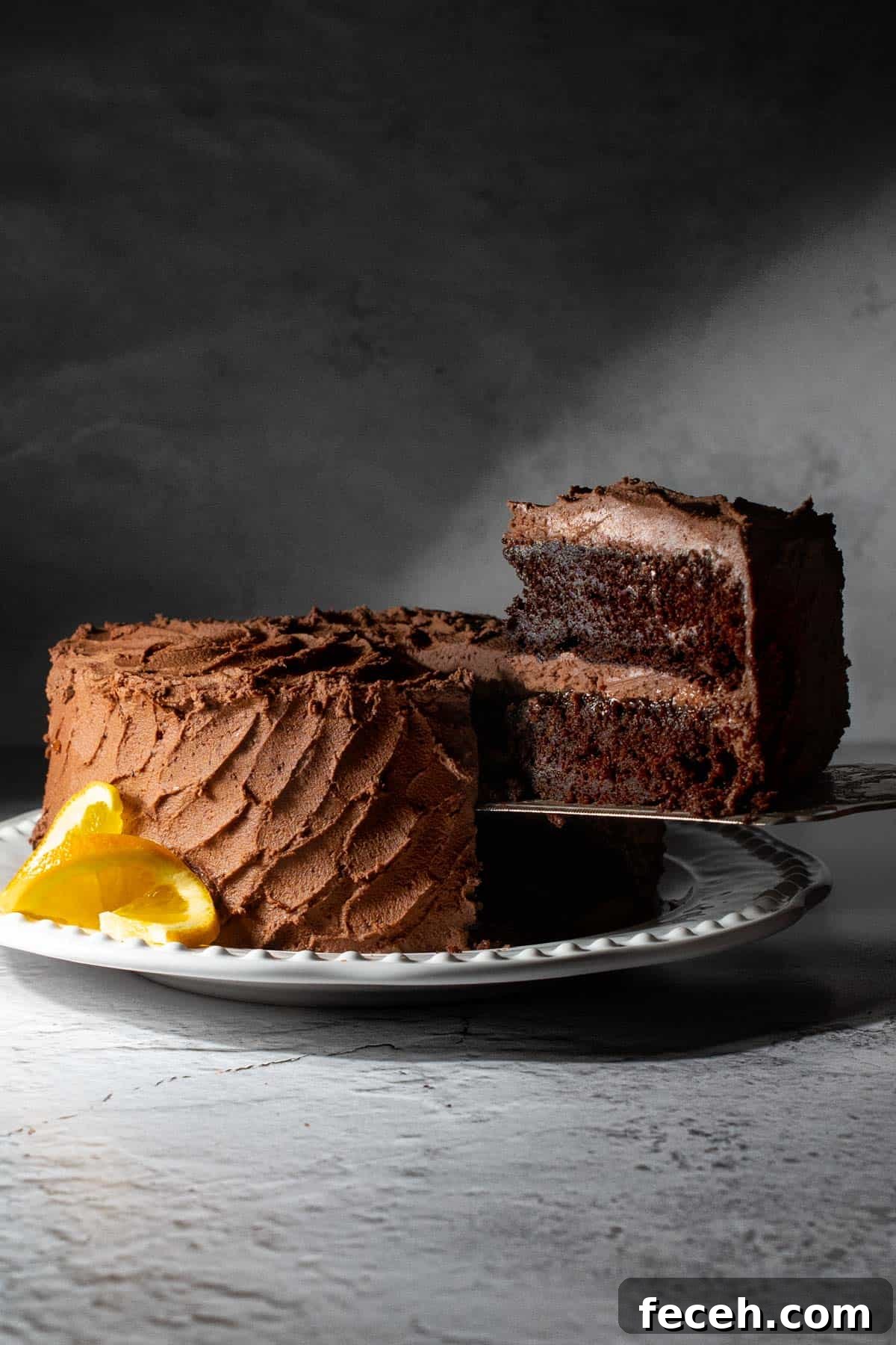 Chocolate orange cake on a white plate with a slice in the foreground.