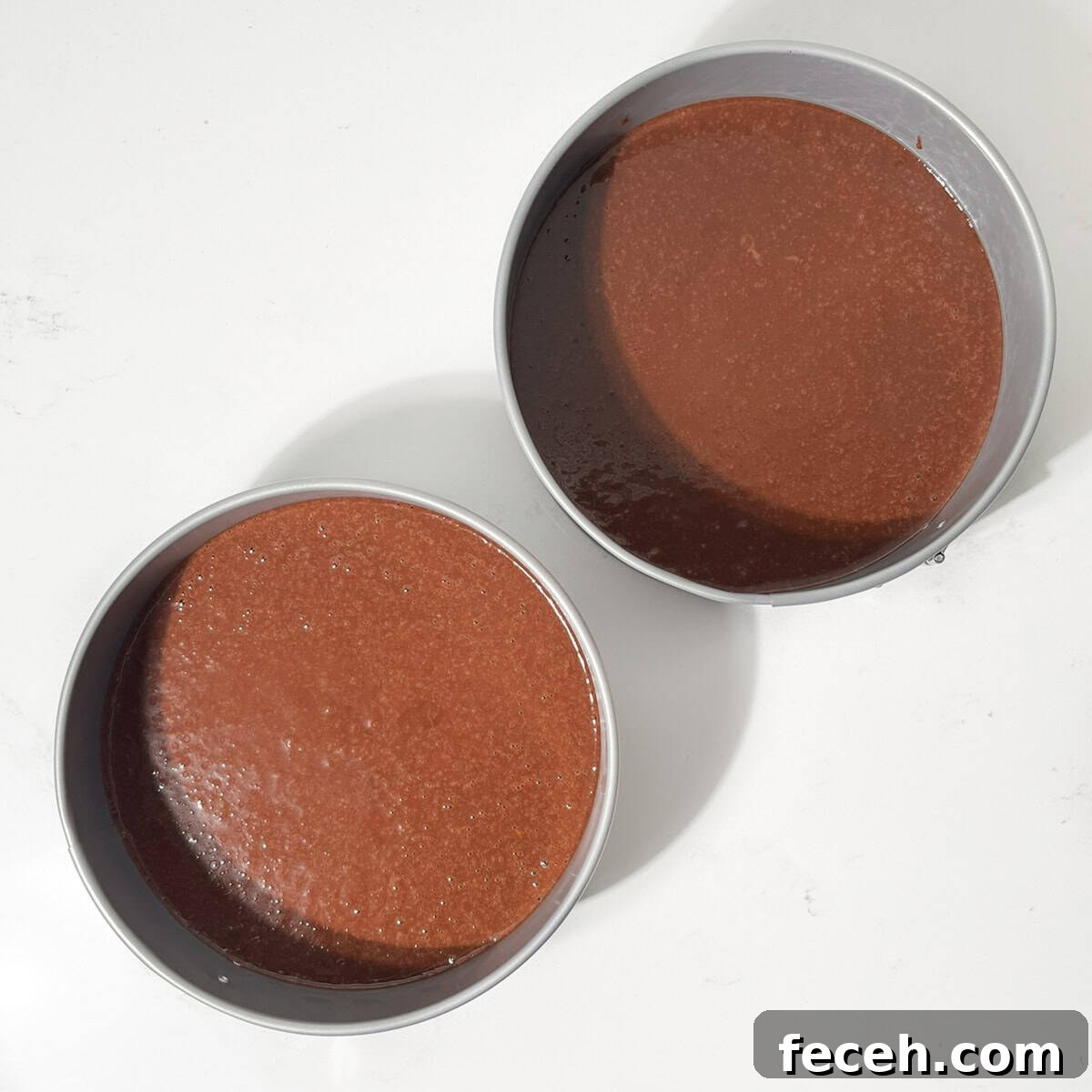 Two round cake tins with chocolate orange batter.