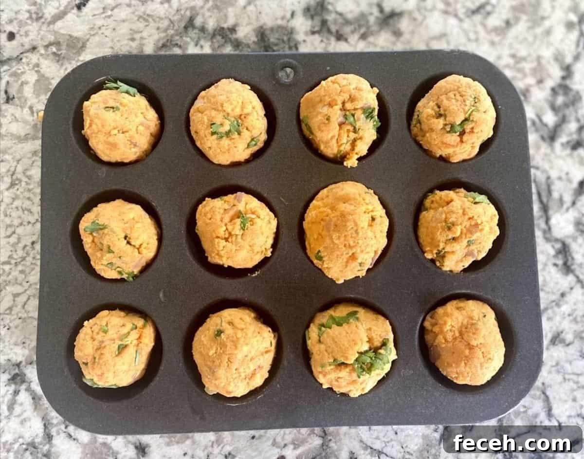 Potato balls inside a mini muffin pan before cooking. 
