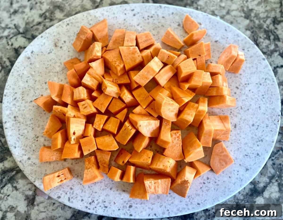 Sweet potatoes are cut into equal-sized pieces on a cutting board. 