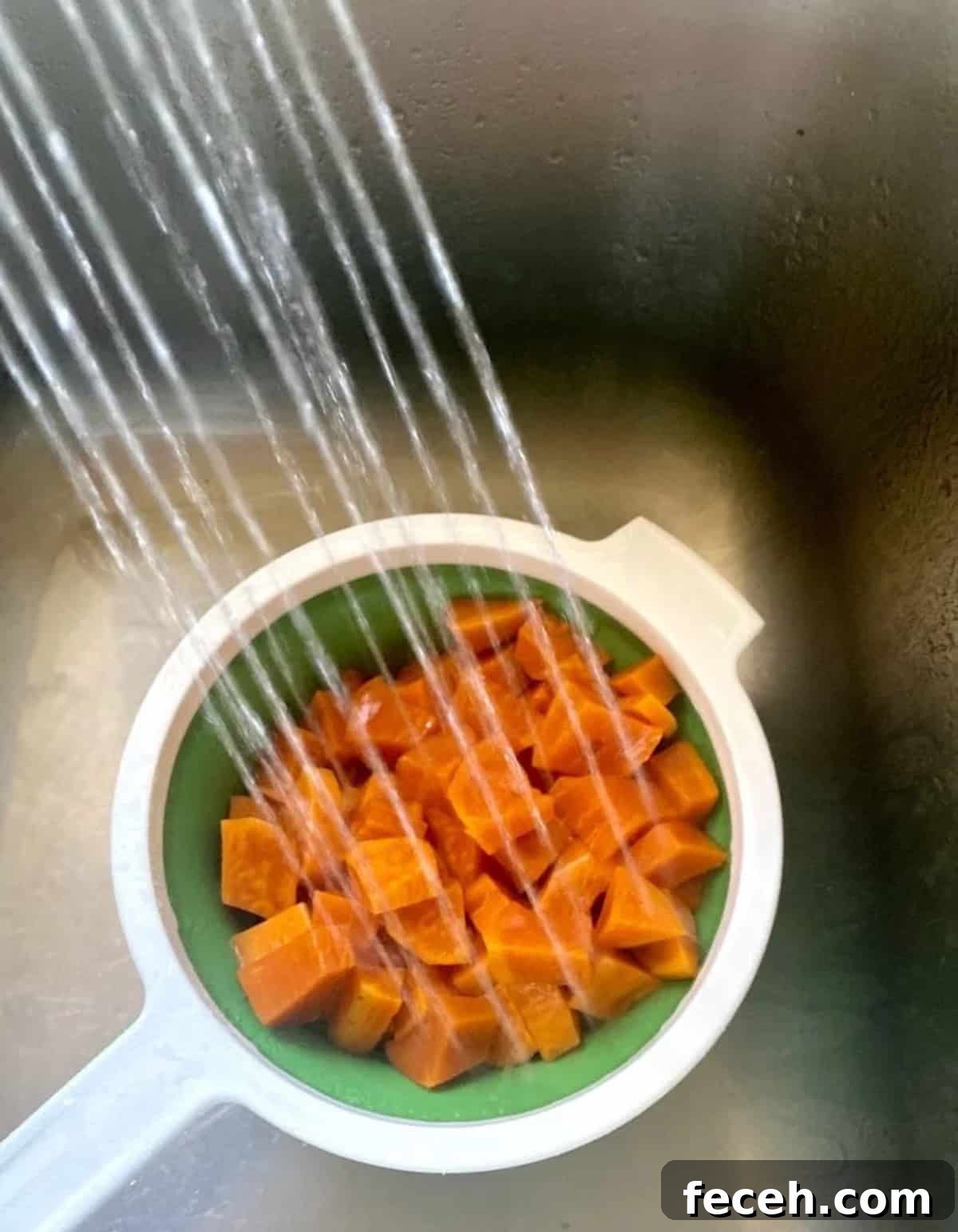 I am rinsing sweet potatoes with cool water after cooking in a colander. 