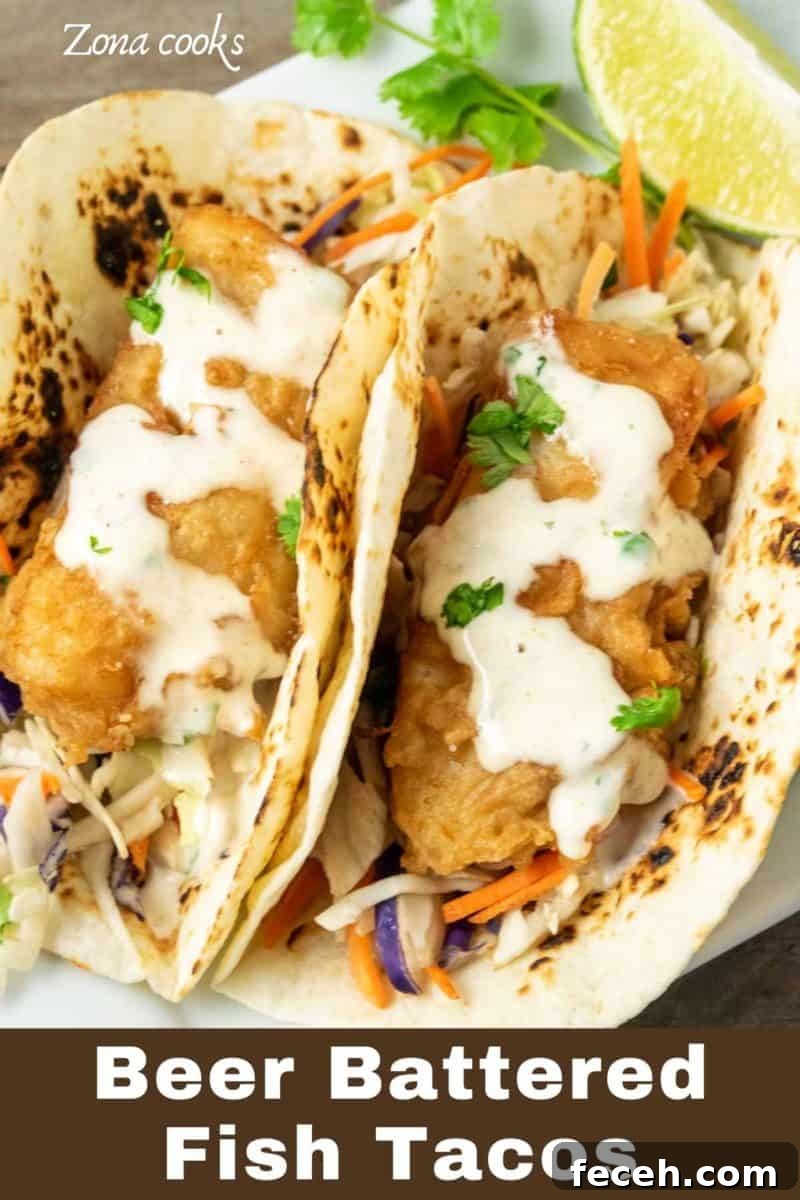 two Beer Battered Fish Tacos with coleslaw on a plate.