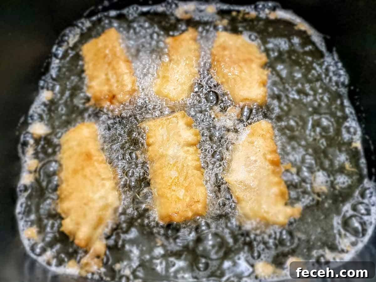 6 beer battered cod filets frying in an electric skillet.