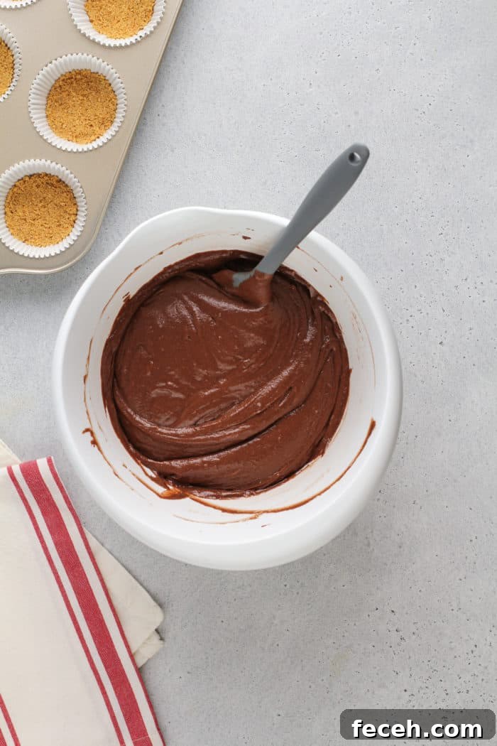 S'mores Cupcakes Recipe: Gooey Campfire Chocolate & Toasted Marshmallow 7 Cake batter for s'mores cupcakes in a white mixing bowl.