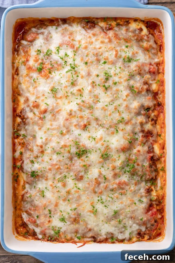 Top down image of baked keto eggplant lasagna with meat sauce in a blue and white casserole dish topped with chopped parsley. 
