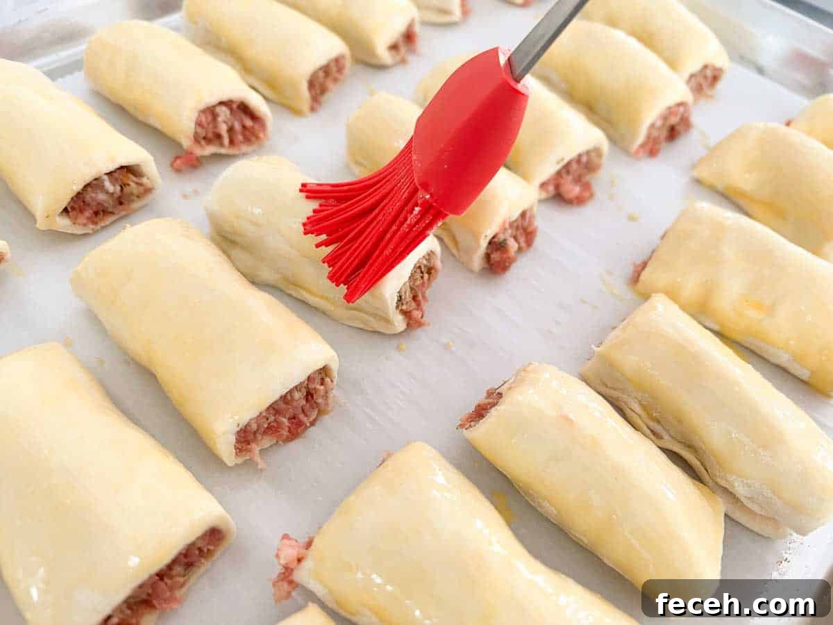 brushing egg wash over sausage rolls
