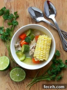 15 Global Soups and Hearty Stews to Warm Any Night 18 A bowl of Mexican chicken soup with corn on the cob, veggies, and lime for serving.