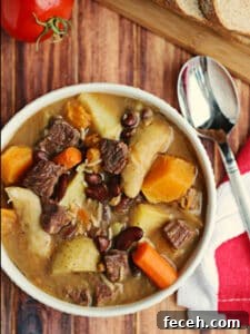 15 Global Soups and Hearty Stews to Warm Any Night 20 A bowl of soup with chunks of beef and pumpkin on a table.