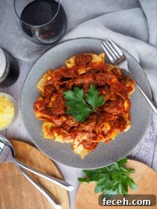 15 Global Soups and Hearty Stews to Warm Any Night 3 Italian ragu over pasta on a plate with wine glasses.