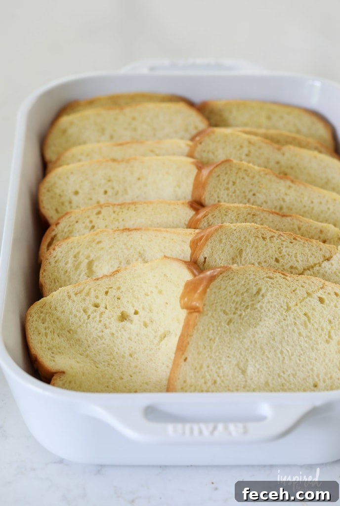 sliced brioche bread arranged in a white baking dish.