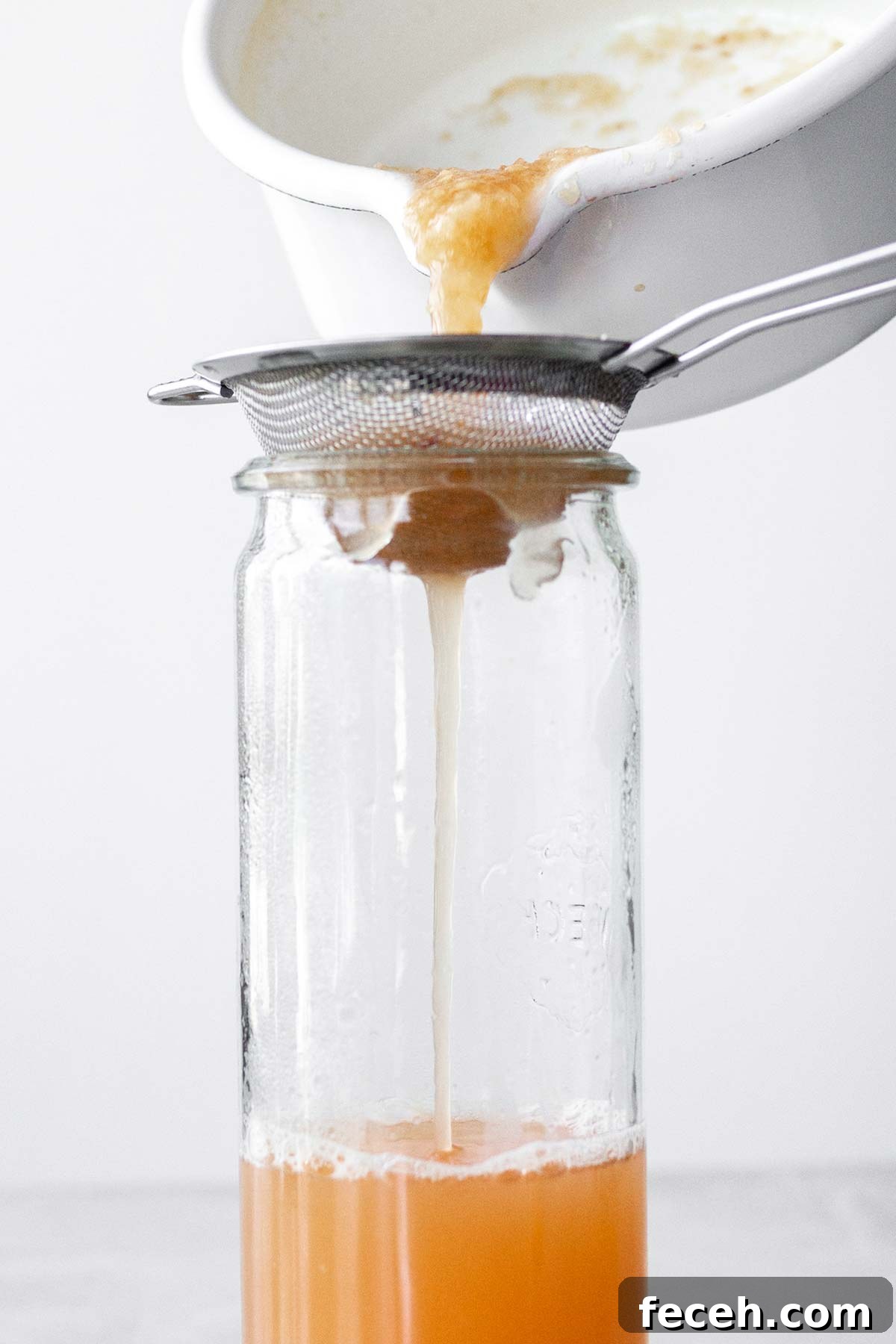 Homemade Peach Syrup Recipe for Cocktails, Pancakes & Desserts 2 Straining peach puree into a glass container.