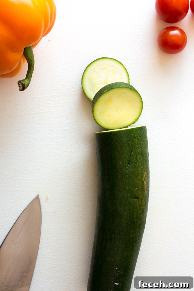 zucchini, bell pepper, and cherry tomato on cutting board with knife