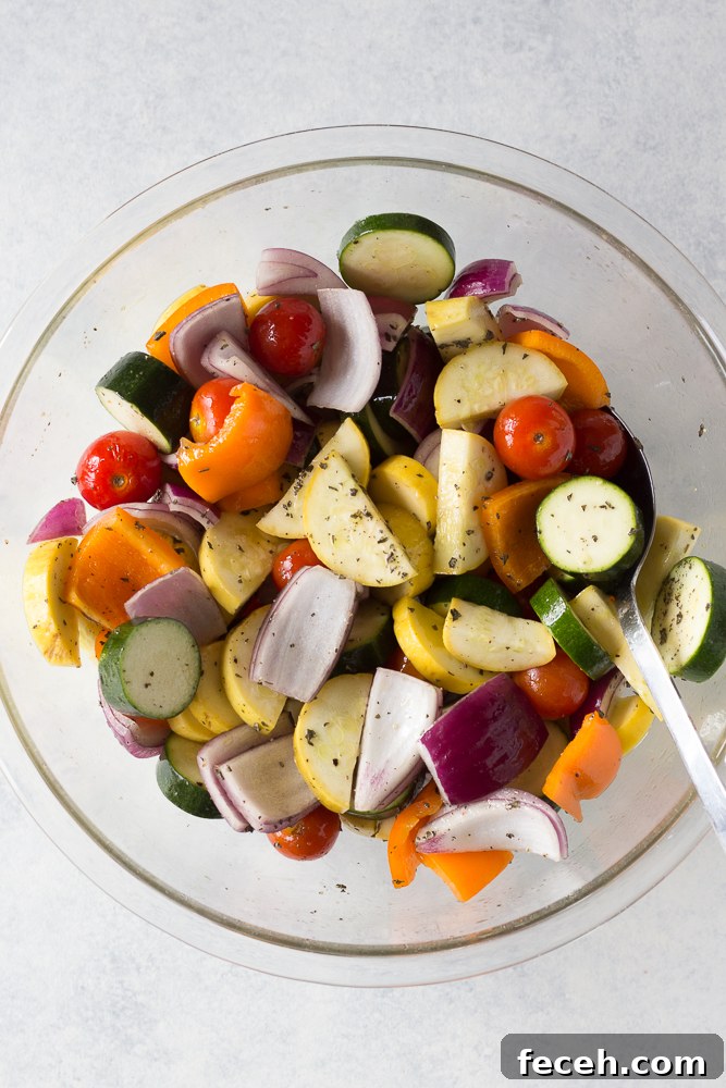 summer vegetables diced in glass bowl with spoon topped with seasonings