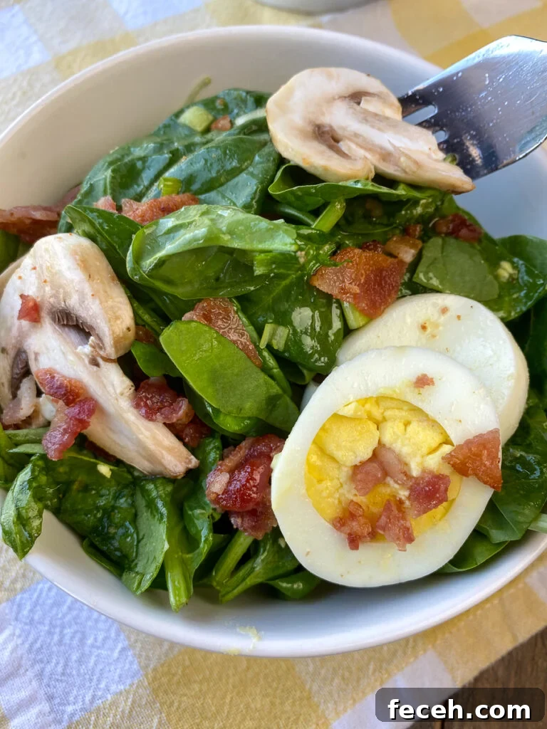 Spinach Salad with Bacon, Mushrooms, and Warm Balsamic Dressing 2 Fork in a small bowl of spinach mushroom salad with bacon, eggs and a light homemade dressing