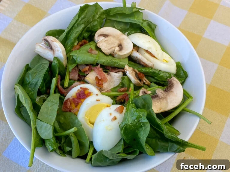 Spinach Salad with Bacon, Mushrooms, and Warm Balsamic Dressing 3 Serving bowl over flowing with baby spinach and topped with fresh mushroom slices, bacon bits and slices of boiled eggs