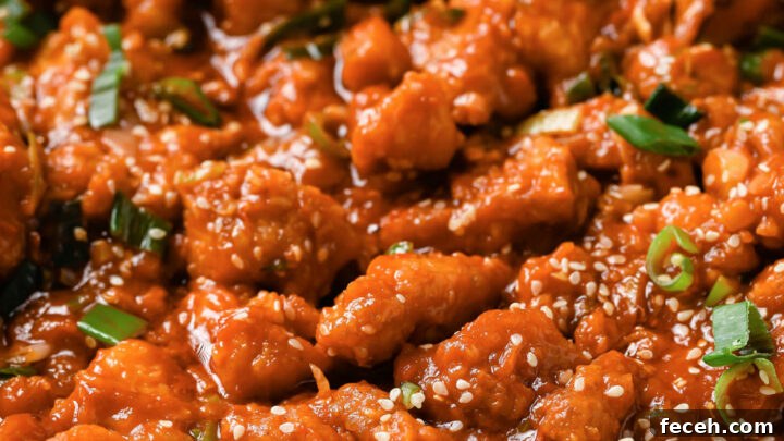 Close up of Chicken Manchurian in pot with a wooden spoon.