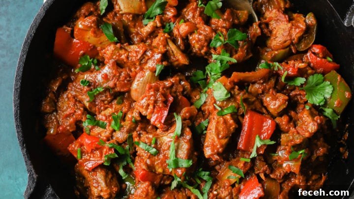 Chicken Jalfrezi in a black skillet with a silver spoon