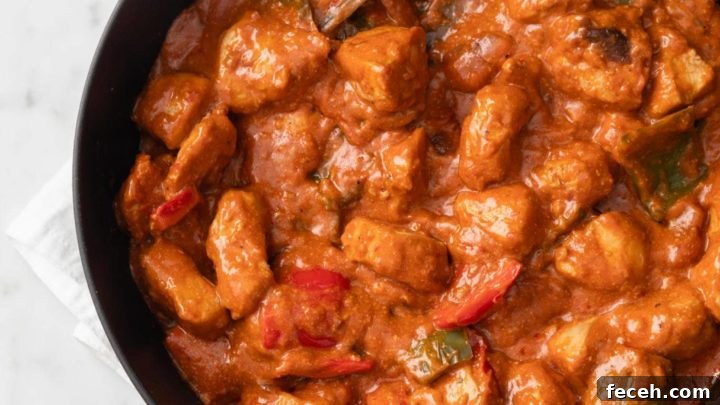 Saucy Chicken Shashlik with bell peppers and onions in a black skillet with a white napkin underneath