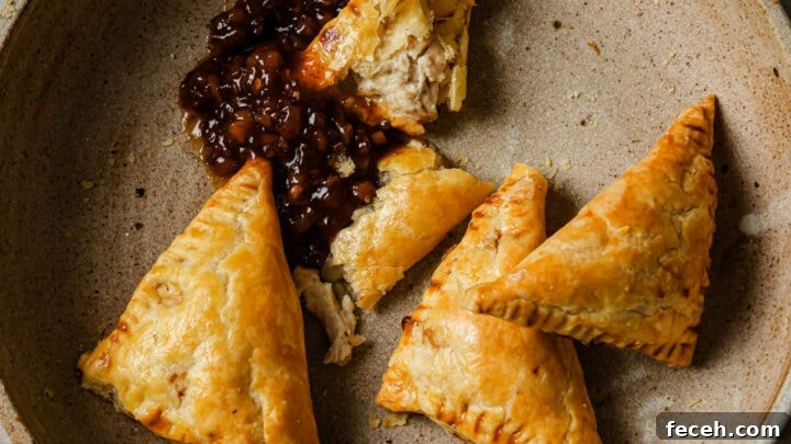 A bowl of partially eaten Chicken Puff Pastires with tamarind chutney.