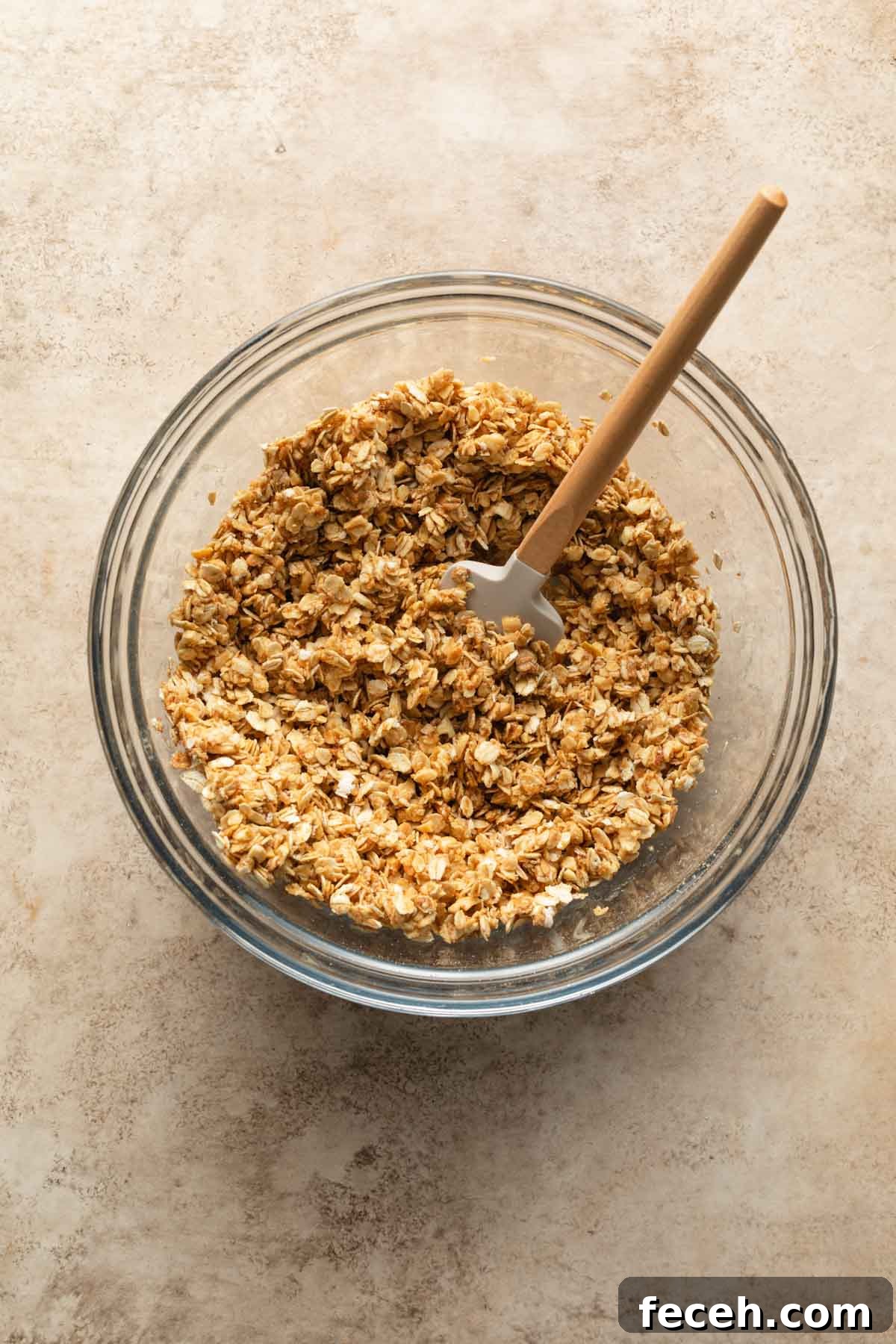 Granola mixed together in a glass bowl with a spatula.