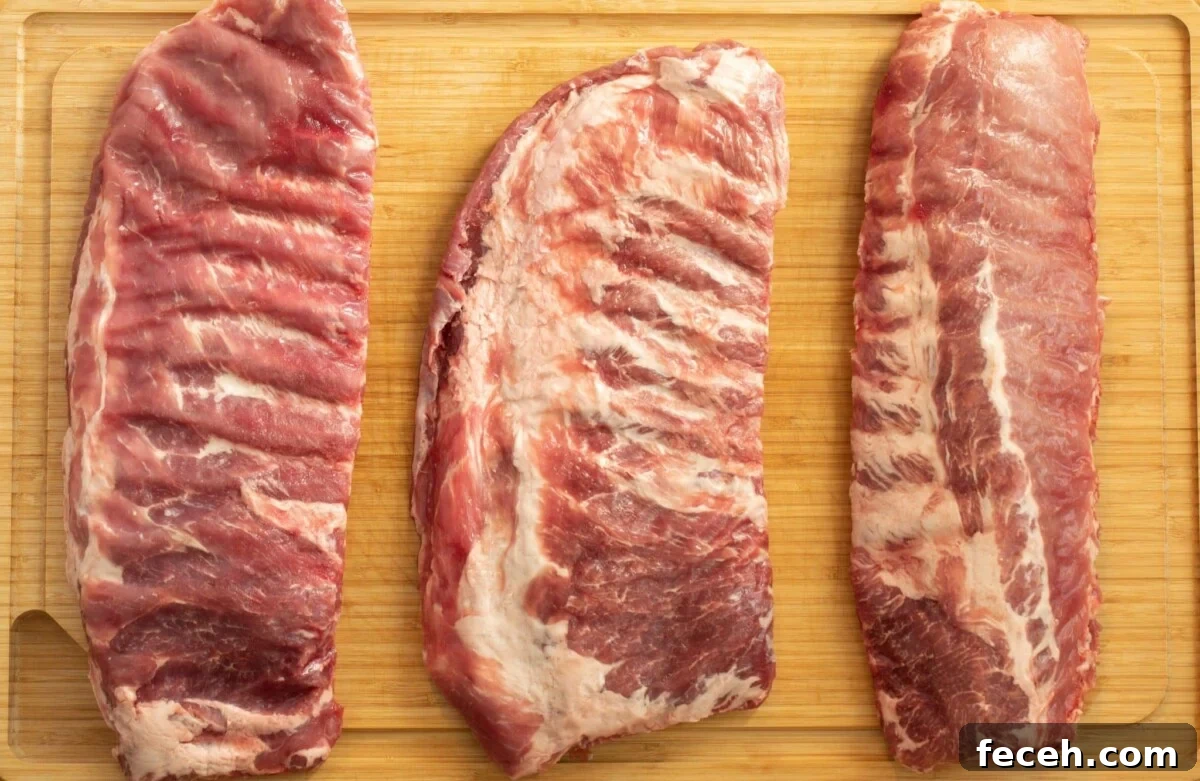 Baby back ribs, spare ribs, and st louis style ribs on a cutting board.