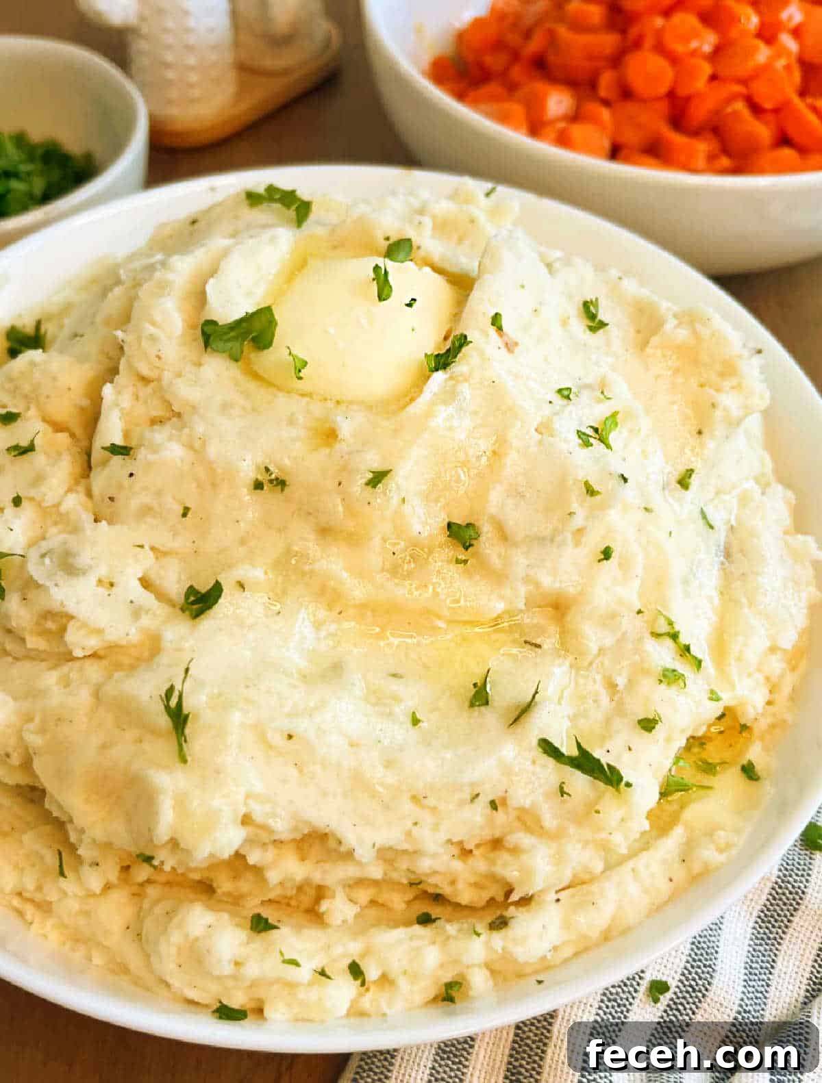 bowl of mashed potatoes with melted butter on table.