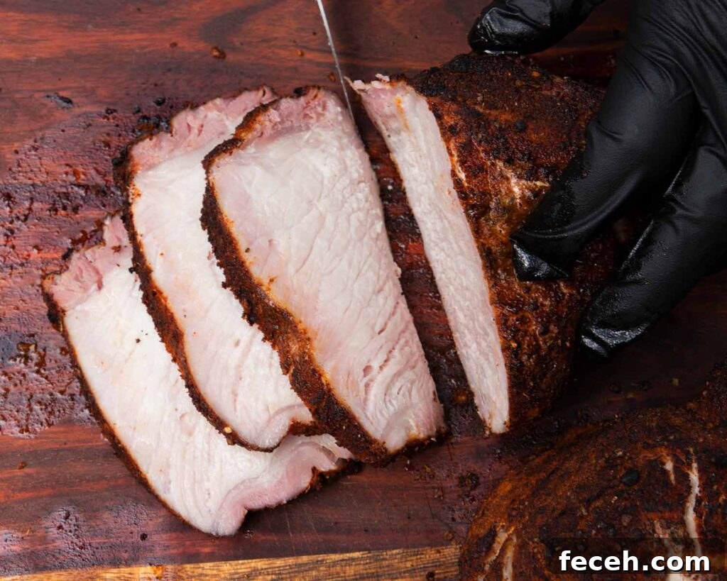 Smoked Double Bone-In Pork Chops with Bold Smoky Flavor 3 Slices of pork from a pork chop on a cutting board.