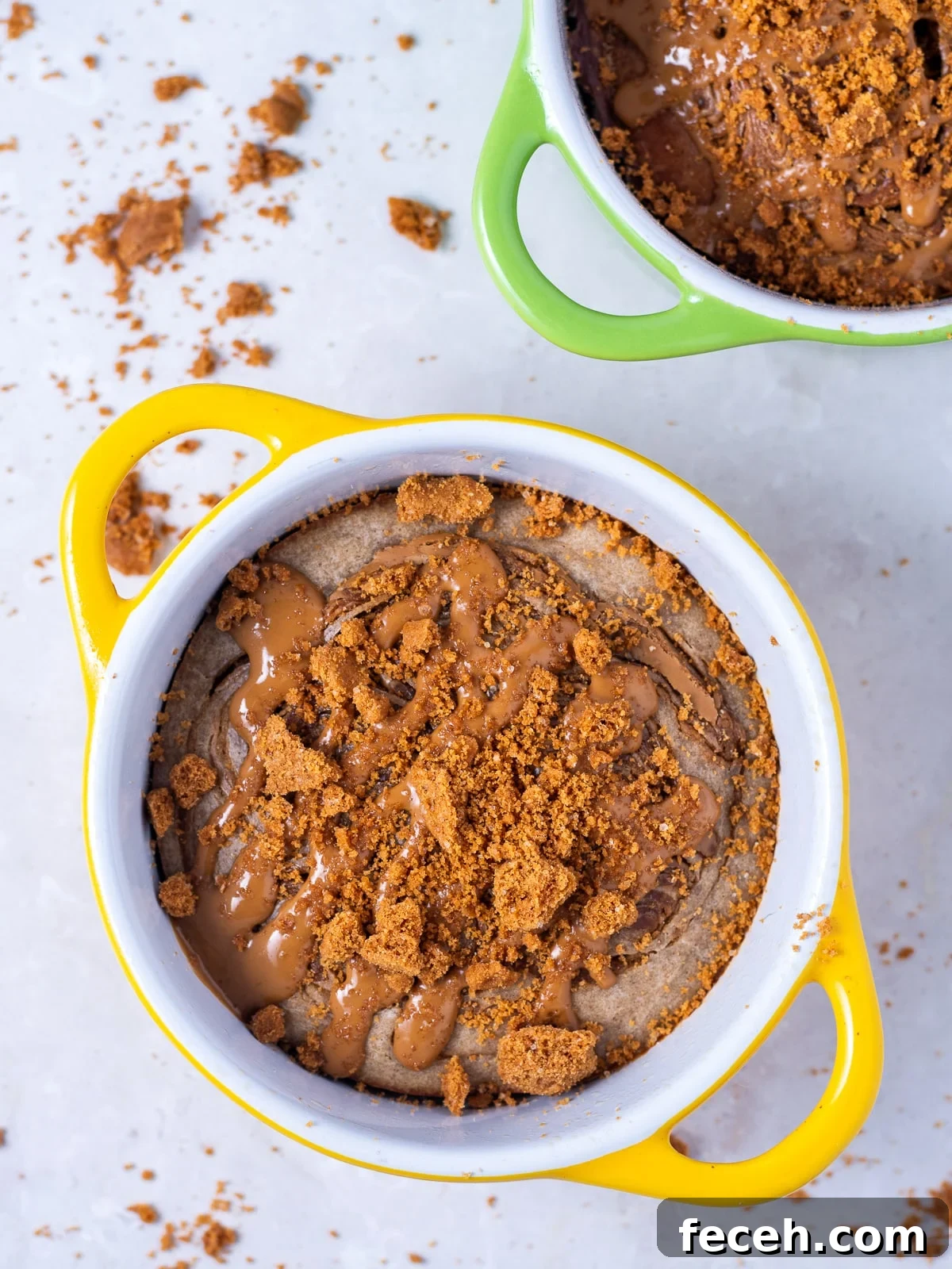 two ramekins of Biscoff baked oatmeal topped with Biscoff spread and biscoff cookie crumble