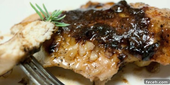 Chicken breast covered in a brown sugar sauce on a white plate. There is a fork holding a small piece of chicken