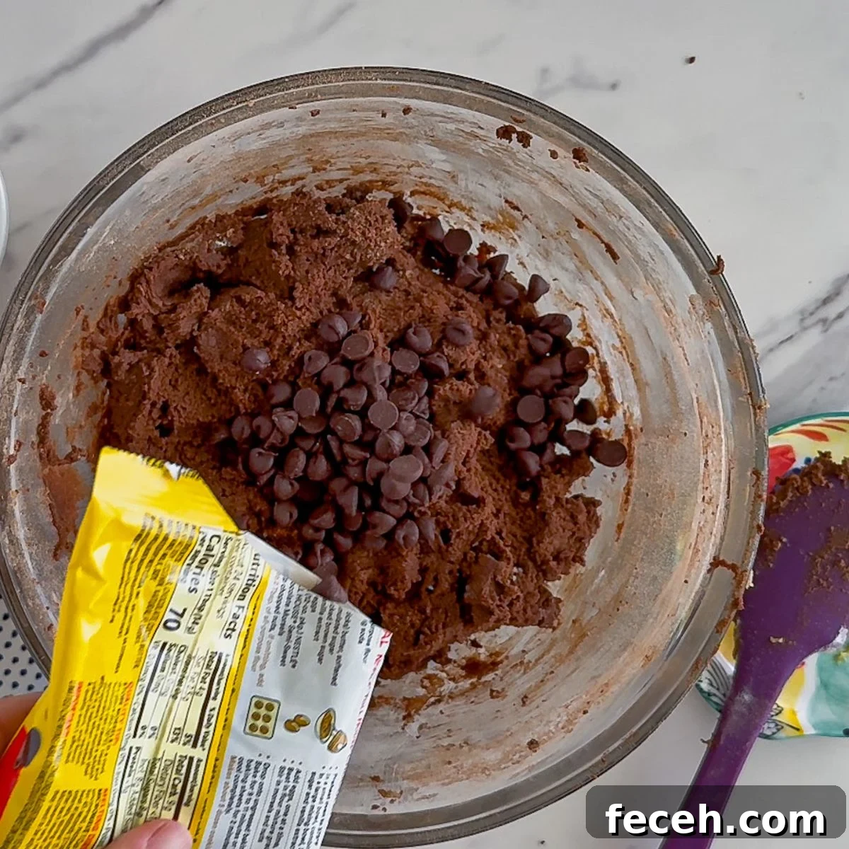 Pouring in the chocolate chips to the cookie dough.