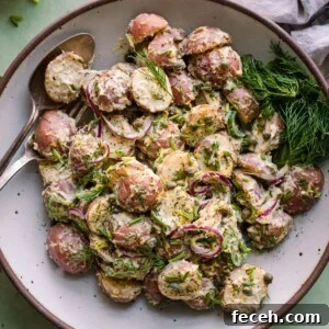 creamy vegan potato salad with dilll in a white bowl on a green backdrop