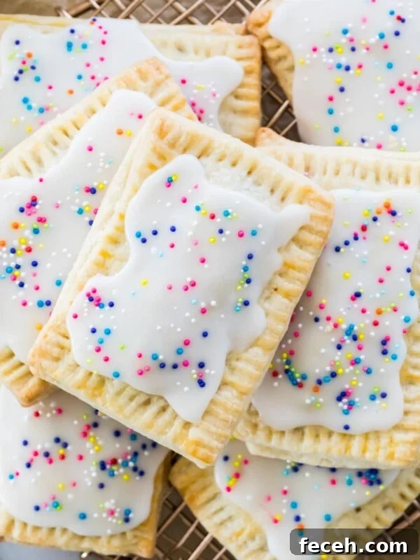 layered pile of homemade strawberry pop tarts topped with rainbow sprinkles on metal cooling rack