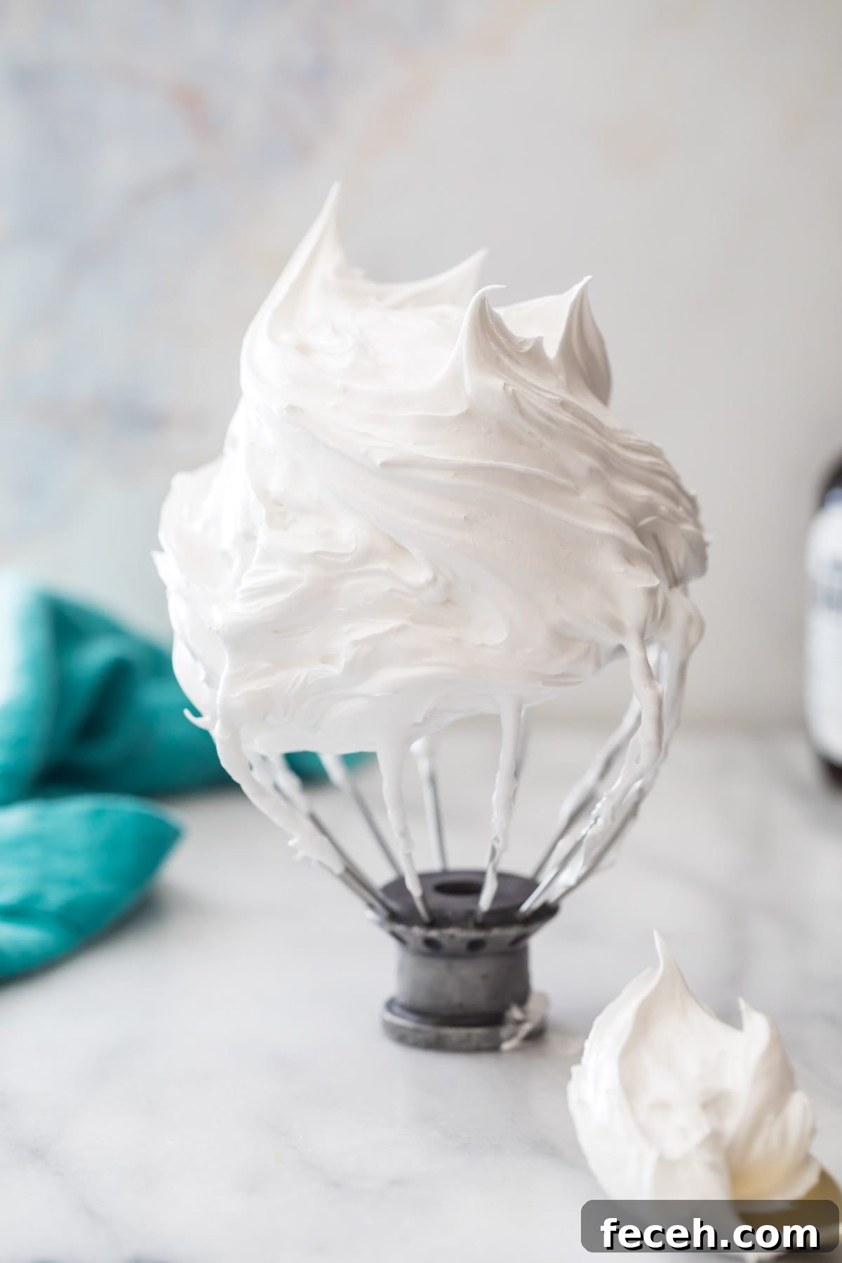 whisk attachment resting upside down on a counter to display stiff peaks in marshmallow cream filling for oatmeal cream pies