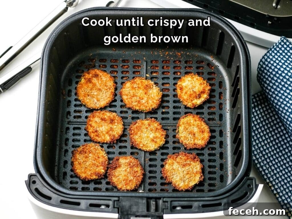 Cooked breaded zucchini rounds in an air fryer basket with text overlay.