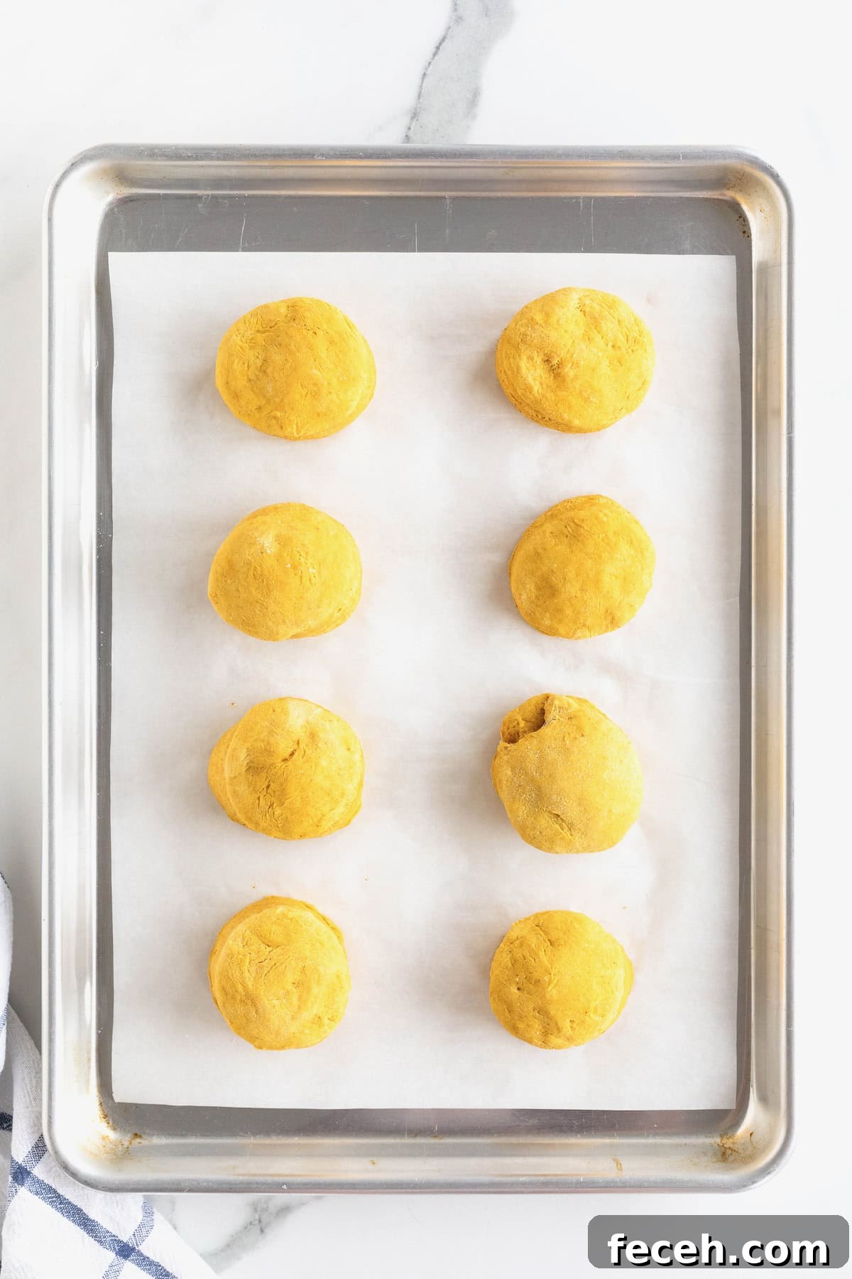 Eight pumpkin muffins on an aluminum baking tray lined with parchment.