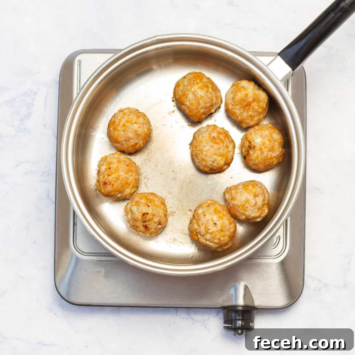 Pesto Chicken Meatballs cooking in cooking pan over heat