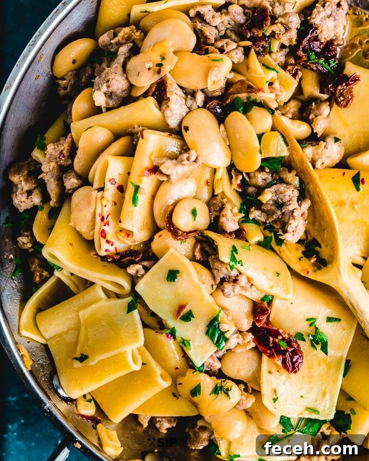 Paccheri Pasta With Butter Beans And Italian Sausage Closeup overhead shot of pasta and beans in pan.